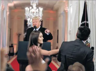  ?? AP PHOTO ?? President Donald Trump watches as a White House aide reaches to take away a microphone from CNN journalist Jim Acosta during a news conference last week in the East Room of the White House in Washington.