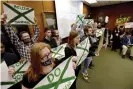  ?? ?? Supporters of victims of sexual abuse by Larry Nassar, hold up signs during a Michigan State Board of Trustees meeting, in December 2017. Photograph: Dale G Young/ AP