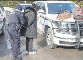  ?? CP PHoTo ?? An asylum claimant claiming to be from Turkey is handcuffed after crossing the border into Canada from the United States near Hemmingfor­d, Que.