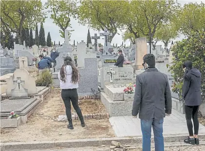  ?? AP ?? Drama. Familiares de fallecidos por Covid-19 en el cementerio de Madrid, con distanciam­iento social.