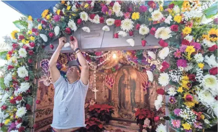  ?? OMAR ORNELAS/USA TODAY NETWORK ?? Martin Esteban arranges flowers on the altar to the Virgin of Guadalupe at the home of Audelio Diaz and Maria Elias near Thermal, Calif. The Purépecha are recognized as some of the finest artisans in Mexico.