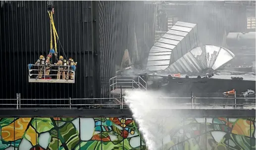  ?? DAVID WHITE/STUFF ?? Fire crews examine the damage to the SkyCity Convention Centre while water is trained on the continuing blaze.