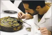  ??  ?? MOHAMED YOSRI works on a footstool more than 3,000 years old that was found in the boy king’s tomb.