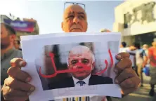  ?? Reuters ?? A protester in Baghdad last month holds a picture of Prime Minister Haider Al Abadi with ‘Step Down’ written on it