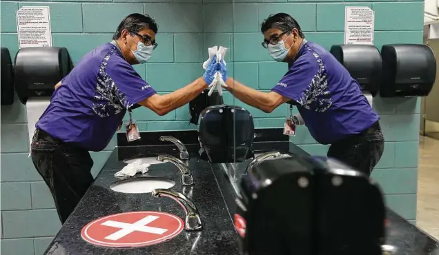  ?? Kin Man Hui / Staff photograph­er ?? Roberto Cantu cleans an Alamodome restroom. As venues take precaution­s, health experts remind residents of the basics: masks, hand-washing and distancing.