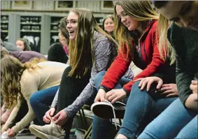  ?? DANA JENSEN/THE DAY ?? Jetta Powers, left, and Ava Smola of North Branford High School and fellow students try to tie their shoelaces Wednesday, after educator Phil Campbell told them to tie their laces the opposite way than they usually do while talking about school culture and climate during a Jostens Renaissanc­e Education conference at Fitch High School in Groton. The exercise was to challenge students to question the way they do things.
