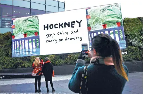  ?? DYLAN MARTINEZ / REUTERS ?? People look at a David Hockney iPad painting as it is displayed on a screen to mark the opening of his Tate Britain retrospect­ive.