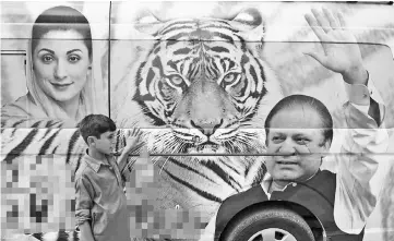  ??  ?? A Pakistani boy stands in front of a van decorated with pictures of Nawaz Sharif (right) and his daughter Maryam Nawaz (left) outside the election campaign office in Rawalpindi. — AFP photo