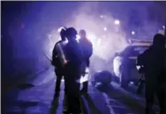  ?? THE ASSOCIATED PRESS ?? Police officers watch protesters as smoke fills the streets Nov. 25, 2014, in Ferguson, Mo.