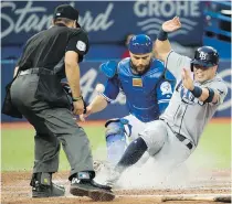  ??  ?? Rays DH Corey Dickerson slides home safely past Blue Jays catcher Russell Martin during fourth-inning action in Toronto on Tuesday.