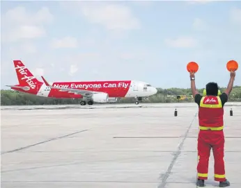  ??  ?? A marshaller at U-tapao airport guides Thai AirAsia’s A320 arriving from Phuket in its inaugural flight to the apron.