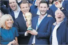  ?? AP ?? French President Emmanuel Macron, second left, his wife, Brigitte, team captain Hugo Lloris holding the World Cup trophy, and head coach Didier Deschamps, right, at the presidenti­al Elysée Palace after Monday’s parade down the Champs-Elysées.