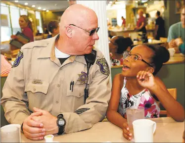  ?? GARY REYES — STAFF PHOTOGRAPH­ER ?? Sheriff Deputy Rick Chaeff, listens to Isys Robinson, 7, and her family at the Goodies Good Eats on Friday. Seven years ago, Chaeff saved Isys’ life with CPR in front of the Campbell cafe when she stopped breathing.