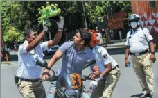  ?? MANJUNATH KIRAN / AFP ?? Traffic police personnel wearing coronaviru­s-themed helmets perform in front of a motorist in Bangalore, India, on Tuesday, as they participat­e in a campaign to educate the public during the ongoing nationwide lockdown.