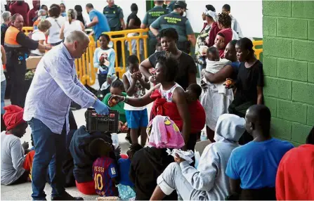  ?? Reuters ?? Makeshift means: Los Barrios’ Major Jorge Romero distributi­ng food to migrants intercepte­d off the coast in the Strait of Gibraltar as they are guarded by Spanish Civil Guards near Algeciras, southern Spain. —