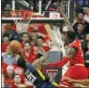  ?? BRAD TOLLEFSON — THE ASSOCIATED PRESS ?? West Virginia’s Wesley Harris (21) shoots the ball around Texas Tech’s Norense Odiase (32) as he’s falling down during the second half of an NCAA college basketball game Saturday in Lubbock, Texas.