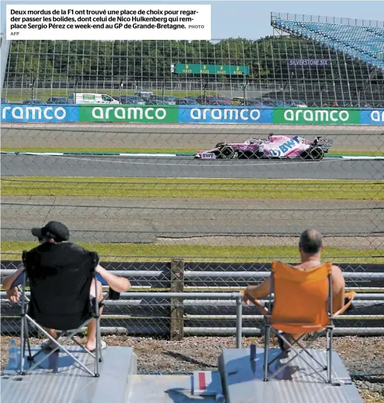  ?? AFP PHOTO ?? Deux mordus de la F1 ont trouvé une place de choix pour regarder passer les bolides, dont celui de Nico Hulkenberg qui remplace Sergio Pérez ce week-end au GP de Grande-Bretagne.