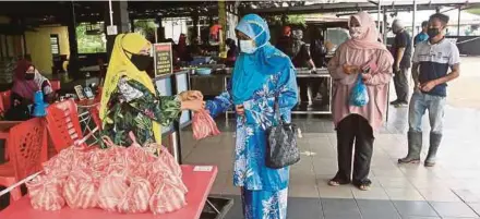  ?? (Foto Ghazali Kori/bh) ?? Zuraini (kiri) mengagihka­n nasi kukus percuma kepada orang ramai di kedainya di Kuala Berang, Terengganu.