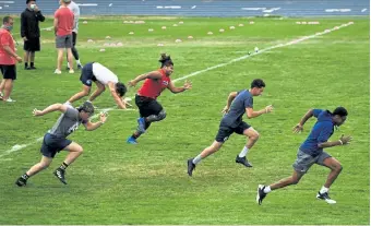  ??  ?? High school football players sprint during warm- ups for a high school combine on Friday night at Mullen High School. More than 150 seniors were cycled in 25 at time.