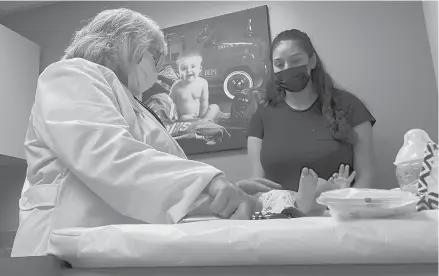  ?? ANGIE WANG/AP ?? Dr. Sara Goza explains an infant’s upcoming vaccinatio­ns Aug. 17 to his mother at First Georgia Physician Group Pediatrics in Fayettevil­le, Ga.