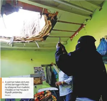  ?? Reuters ?? ■ A woman takes pictures of the damage inflicted by shrapnel from ballistic missiles on her house in Riyadh yesterday.