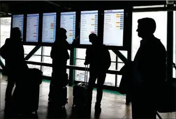  ?? NAM Y. HUH — THE ASSOCIATED PRESS ?? Travelers check American Airlines flight informatio­n screens for their flight status at O'Hare Internatio­nal Airport in Chicago, Wednesday. More than 100flights are canceled as portions of the greater Chicago area could see freezing rain and ice.