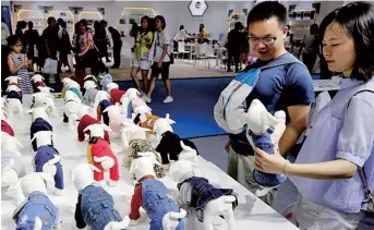  ??  ?? Various designs for dog clothes are displayed at the fair. Pet owners are keen to provide the best supplies they can afford for their animals. — Xinhua