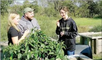  ?? Lynn Atkins/The Weekly Vista ?? Kadence Flynn and Unit Program Manager Shawn Sawyer watch as Jada Moore prepares to taste a jalapeno pepper grown by members of the Torch Club at the Bella Vista Unit of the Boys & Girls Club of Benton County.