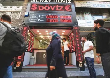  ?? AP ?? People walk past a currency exchange outlet in Istanbul on Tuesday. Tensions between Turkey and the Trump administra­tion have been centred on a dispute over the detention of an American pastor, which resulted in tariffs and sanctions.