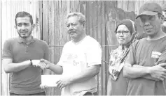  ??  ?? Nik Nazri (second left) presents contributi­on to Registly in the presence of family members and Keningau Informatio­n Department acting officer Hendry Nurdin (left).