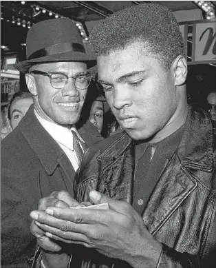  ?? AP PHOTO ?? In this March 1, 1964, file photo, world heavyweigh­t boxing champion, Muhammad Ali, right, is shown with Black Muslim Leader, Malcolm X, outside the Trans-lux Newsreel Theater on Broadway at 49th Street in New York City. They had just watched a...