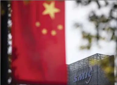  ?? (Bloomberg/Qilai Shen) ?? A Chinese flag is seen near a logo atop the Semiconduc­tor Manufactur­ing Internatio­nal Corp. headquarte­rs in Shanghai in March 2021.