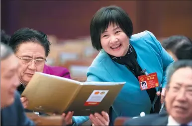  ?? XU JINGXING / CHINA DAILY ?? Fu Qionghua, a deputy from Jiangxi province, invites other delegates to sign their names on the two sessions’ commemorat­ive album during a break at the third plenary meeting of the fifth session of the 12th National People’s Congress in Beijing on...