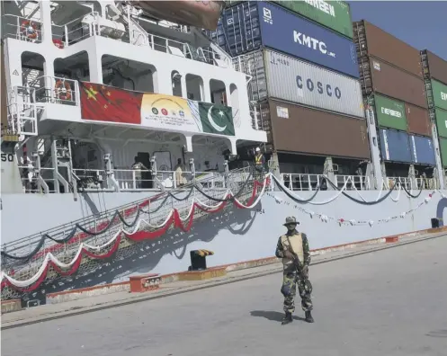  ??  ?? 0 A Pakistan soldier stands guard while a loaded Chinese ship prepares to leave the deepwater port of Gwadar on the Arabian Sea