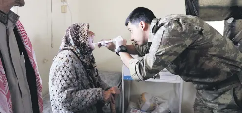  ??  ?? A Turkish officer treats an Afrin local at a medical clinic in rural Afrin.