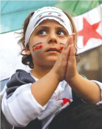  ?? AFP ?? A Syrian girl claps as she takes part in a protest against the regime in the town of Kafr Takharim in Idlib governorat­e.