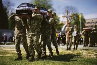  ?? Leon Neal / Getty Images ?? Soldiers carry the coffins of three of their comrades during a burial ceremony in Lviv, Ukraine. The Kremlin’s forces have redoubled their efforts to capture the eastern Donbas region.