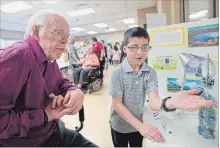  ?? PETER LEE WATERLOO REGION RECORD ?? Quinn Plummer, an “enthusiast­ic” Grade 4 student at Northlake Woods Public School, explained his solar power technology display to Phil Fiess.