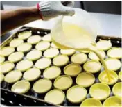  ??  ?? Custard being poured into the pastry molds at Lord Stow’s bakery in Macau.