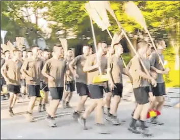  ?? Television Broadcasts Limited Hong Kong ?? In this image made from video, Chinese People’s Liberation Army soldiers, carrying brooms, arrive to clean up protest debris Saturday at Hong Kong Baptist University.