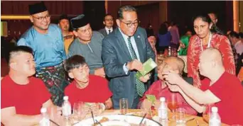  ?? PIC BY ZULKARNAIN AHMAD TAJUDDIN ?? Johor Menteri Besar Datuk Seri Mohamed Khaled Nordin giving out duit raya during a Hari Raya Aidilfitri open house hosted by the Iskandar Regional Developmen­t Authority in Johor Baru yesterday. With him is Irda chief executive Datuk Ismail Ibrahim (on...