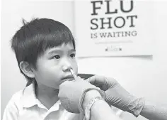  ?? Ellen M. Banner/Seattle Times/TNS ?? ■ Brayden Yee of Shoreline, Wash., receives a dose of FluMist from a Bartell Drugs pharmacist in 2014.