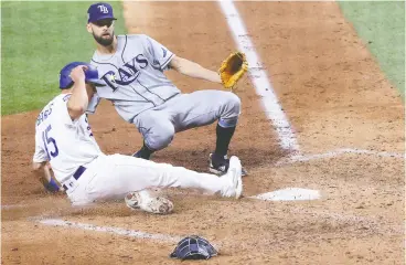  ?? SEAN M. HAFFEY / GETTY IMAGES ?? Austin Barnes of the Los Angeles Dodgers slides in safely past the Tampa Bay Rays’ Nick Anderson to score on a wild pitch during the sixth inning in Game 6 of the 2020 World Series. Despite pitching poorly in the series, Anderson was brought in to
replace starting pitcher Blake Snell, who had been brilliant.