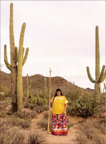  ?? CASSIDY ARAIZA — FOR THE WASHINGTON POST ?? Jacelle E. Ramon-sauberan, in traditiona­l Tohono O’odham dress, is pictured with a kuipud that is used to pick cactus fruit. The saguaro fruit, which tastes a little like strawberry, can be eaten raw or made into jam, syrup and wine.