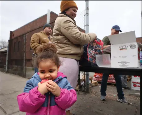  ?? NANCY LANE — BOSTON HERALD ?? Two-year-old Vanessa Pina eats an apple as her mother, Irlanda, picks up provisions at the Salvation Army Food Pantry in Chelsea Thursday.