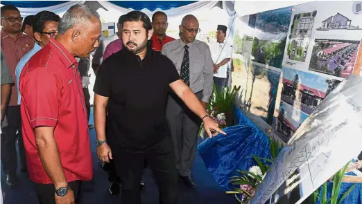  ??  ?? Royal concern: Tunku Ismail finding out more about the Bangsa Johor dream house project from Asman Shah (left) during the ground-breaking ceremony of the project at Kampung Sri Pantai in Mersing. — BernamaBy REMAR NORDIN newsdesk@thestar.com.my