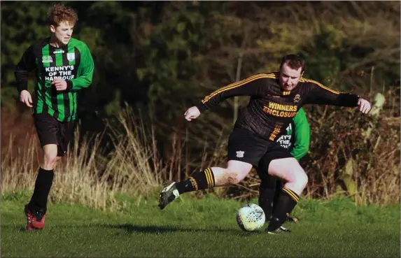  ??  ?? Harry Newsome of Arklow United keeps a close eye on John Kavanagh of Carnew AFC.