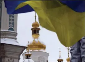  ?? EFREM LUKATSKY — THE ASSOCIATED PRESS ?? An Ukrainian national flag flutters in the wind as people gather to support independen­t Ukrainian church Saturday near the St. Sophia Cathedral in Kiev, Ukraine. Ukraine’s Orthodox clerics gathered for a meeting Saturday to form a new, independen­t Ukrainian church, and Ukrainian authoritie­s have ramped up pressure on priests to support the move.