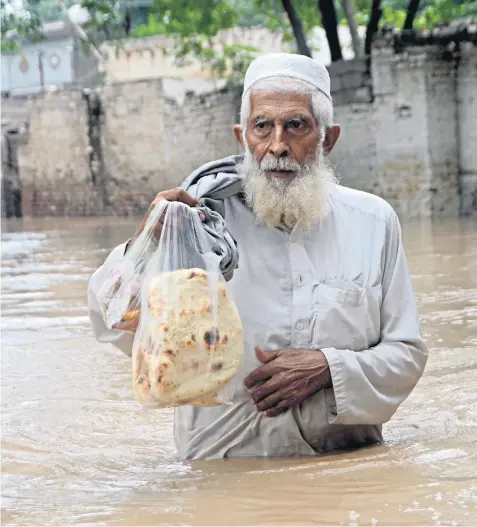  ?? ?? A man wades through a flooded area in Peshawar, Khyber Pakhtunkhw­a. Nearly 10 million have been displaced and 300,000 homes have been destroyed by an ‘epic’ deluge