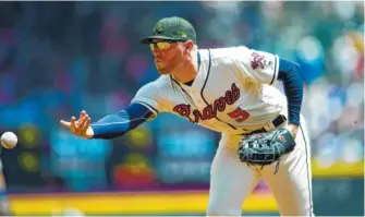  ?? AP PHOTO/JOHN AMIS ?? Atlanta Braves first baseman Freddie Freeman tosses the ball to pitcher Mike Foltynewic­z at first base to get Milwaukee’s Christian Yelich out Sunday in Atlanta. The Brewers won 3-2.